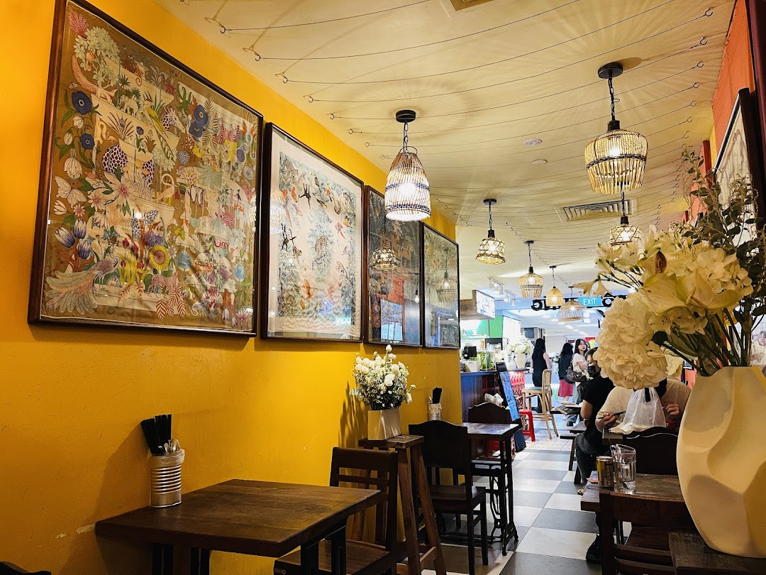 A vibrant interior shot of Co Chung Vietnamese Restaurant, featuring colorful wall art, rattan lighting, and cozy wooden tables.