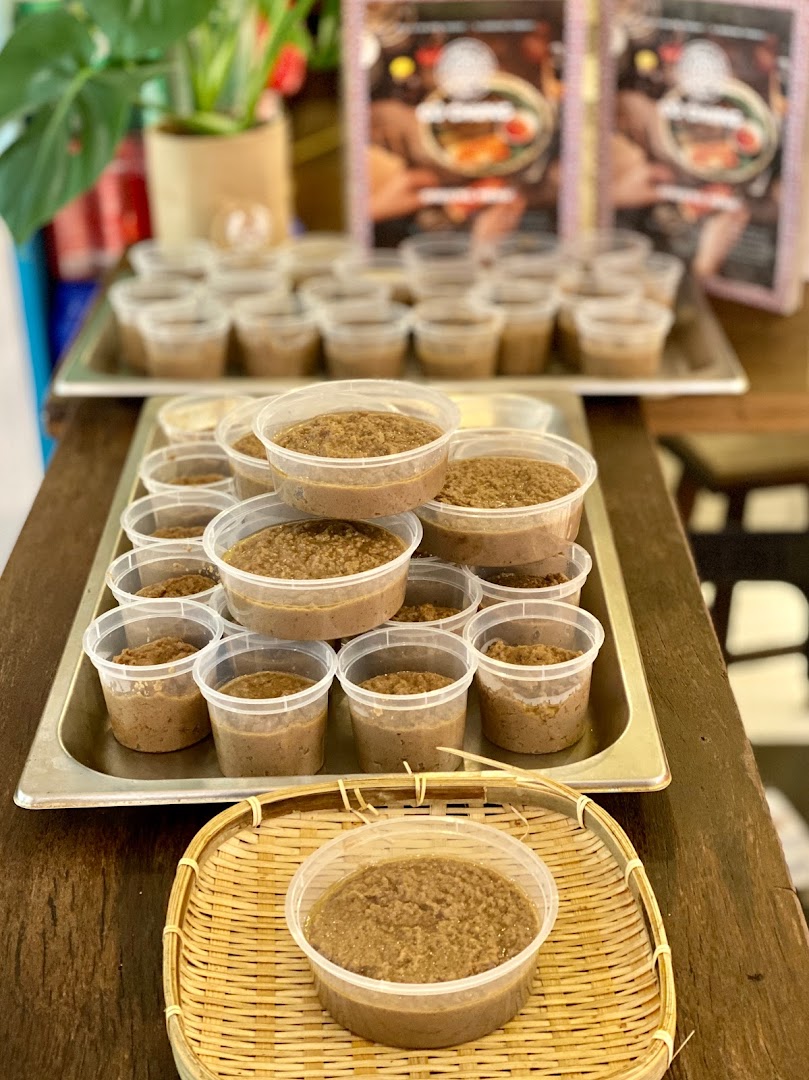 Numerous plastic containers filled with a brown, textured food product, likely a sauce or paste, displayed for sale.