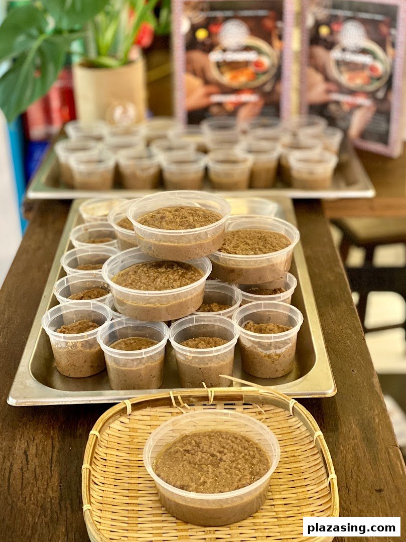 Numerous plastic containers filled with a brown, textured food product, likely a sauce or paste, displayed for sale.