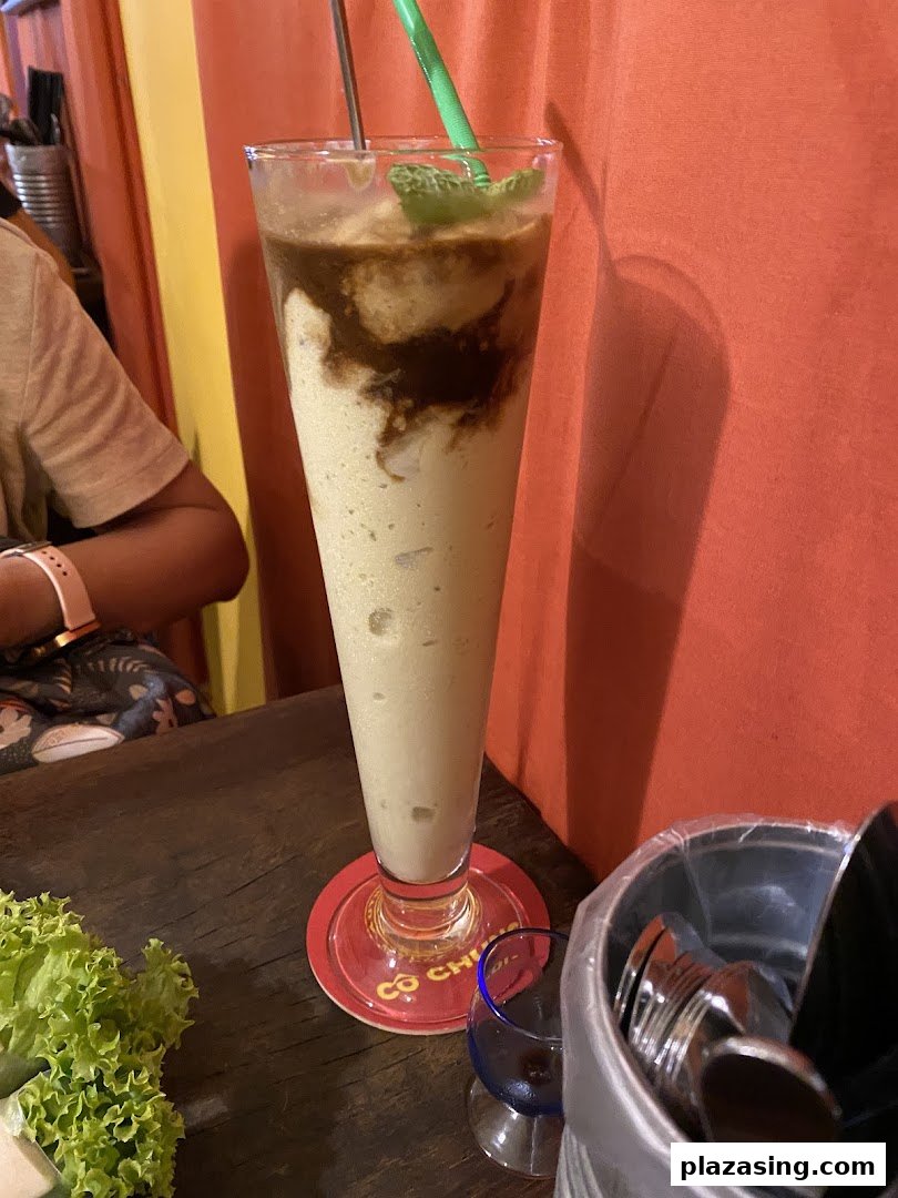 A refreshing blended drink with mint and chocolate drizzle on a wooden table at Co Chung.