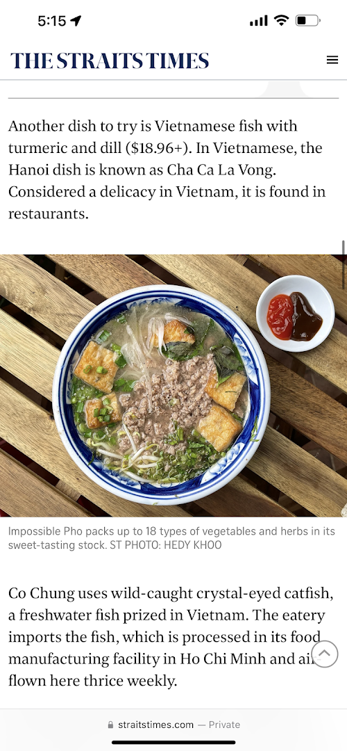 A delicious bowl of Vietnamese Impossible Pho with various ingredients and sauces on a wooden table.