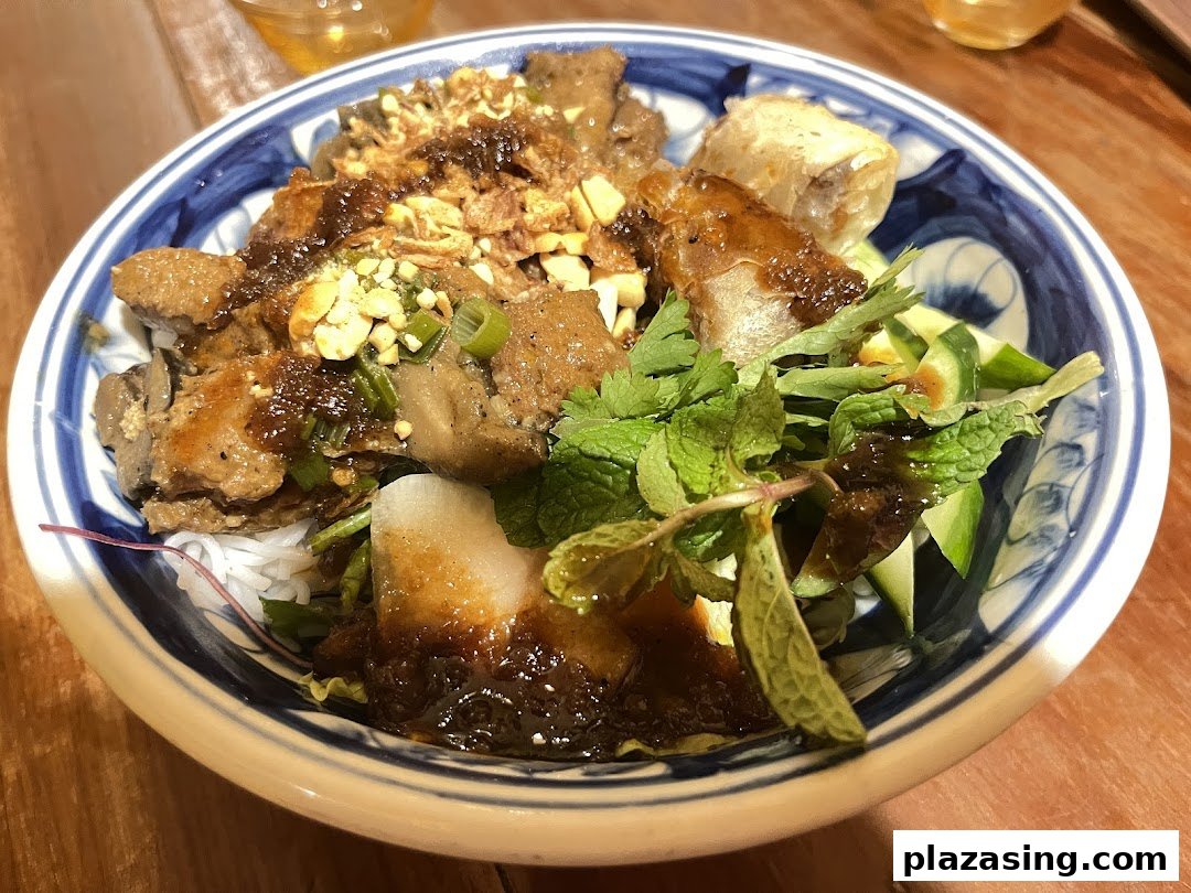 A vibrant bowl of Vietnamese noodles with grilled meat, fresh herbs, and a savory sauce.