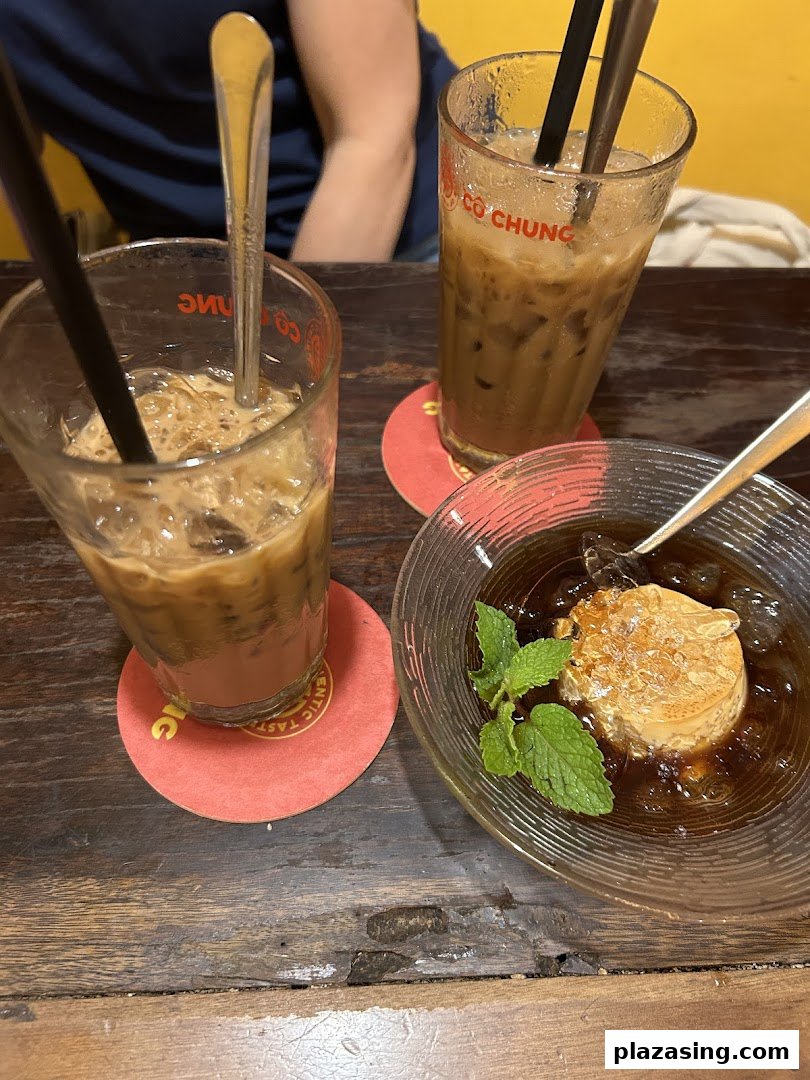 Two iced Vietnamese coffees and a traditional dessert with mint on a rustic wooden table.