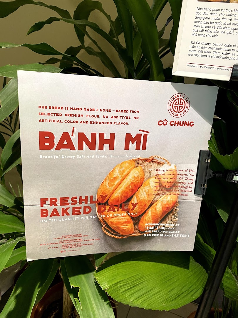 A promotional sign for Co Chung's freshly baked Bánh Mì bread, detailing ingredients and pricing.