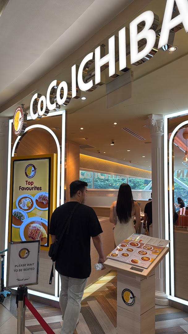 The brightly lit entrance of CoCo ICHIBANYA, a Japanese curry restaurant, with customers entering.