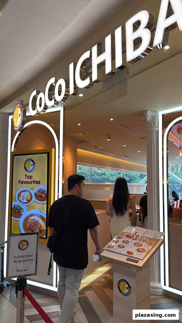 The brightly lit entrance of CoCo ICHIBANYA, a Japanese curry restaurant, with customers entering.