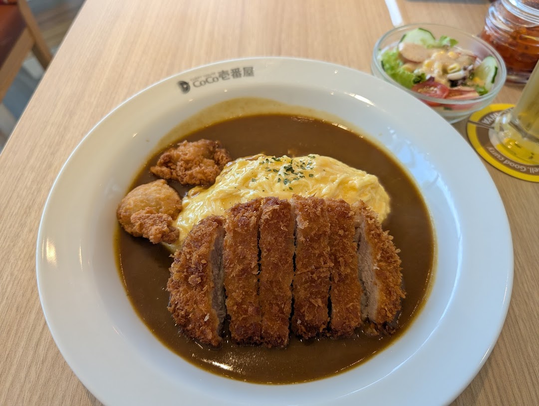 A delicious plate of Japanese curry with crispy tonkatsu, fluffy omelet, and a side salad.