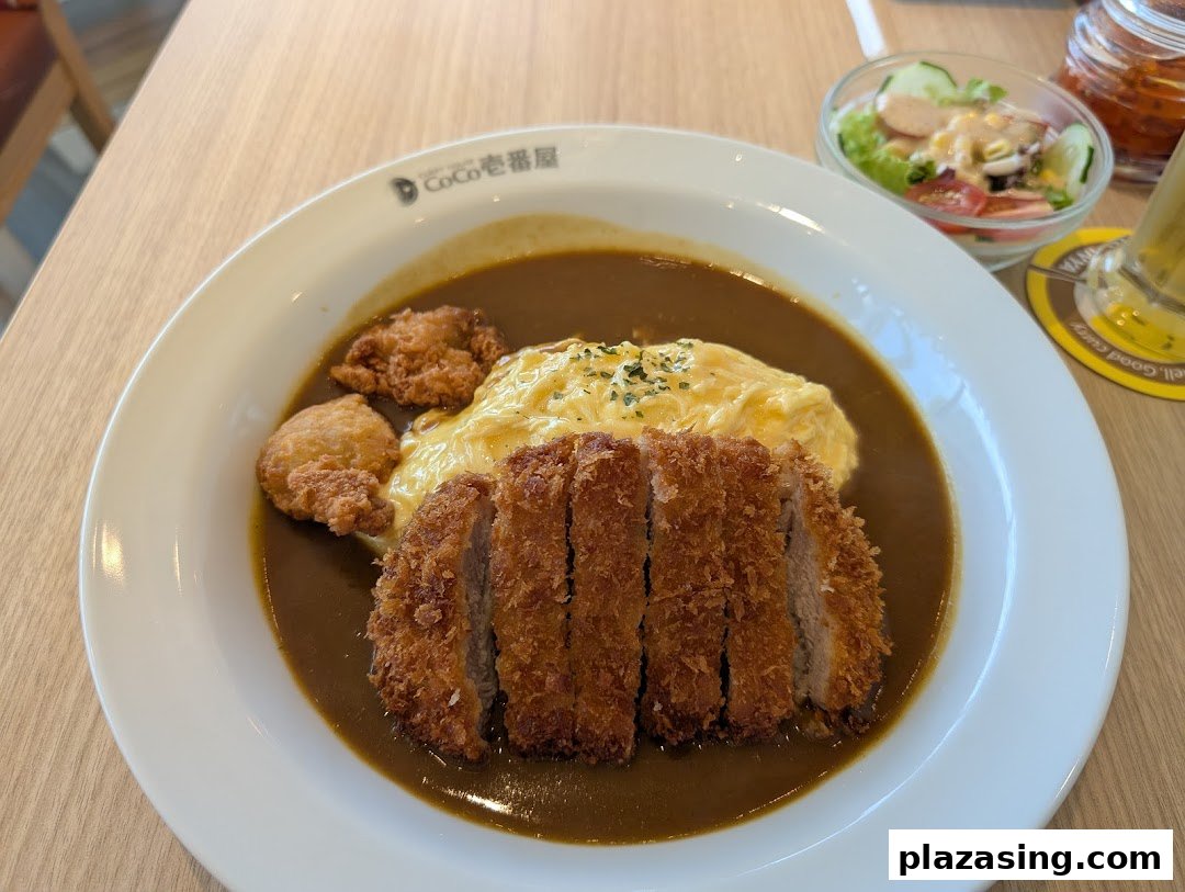 A delicious plate of Japanese curry with crispy tonkatsu, fluffy omelet, and a side salad.