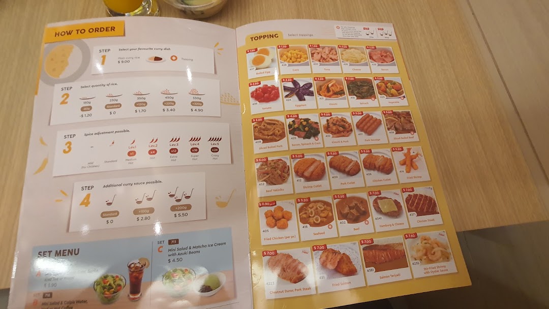 A detailed menu from CoCo ICHIBANYA showing curry customization options and a wide range of toppings.