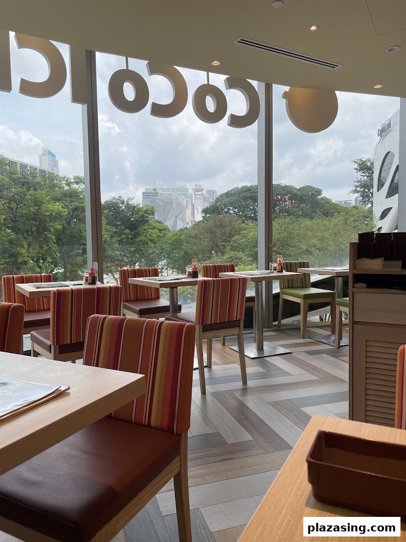 Spacious dining area at CoCo ICHIBANYA with comfortable seating and a scenic city view through large windows.
