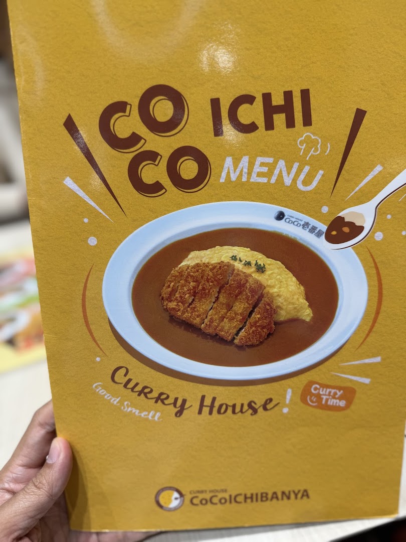 The vibrant yellow cover of a CoCo ICHIBANYA menu featuring a delicious katsu curry dish.