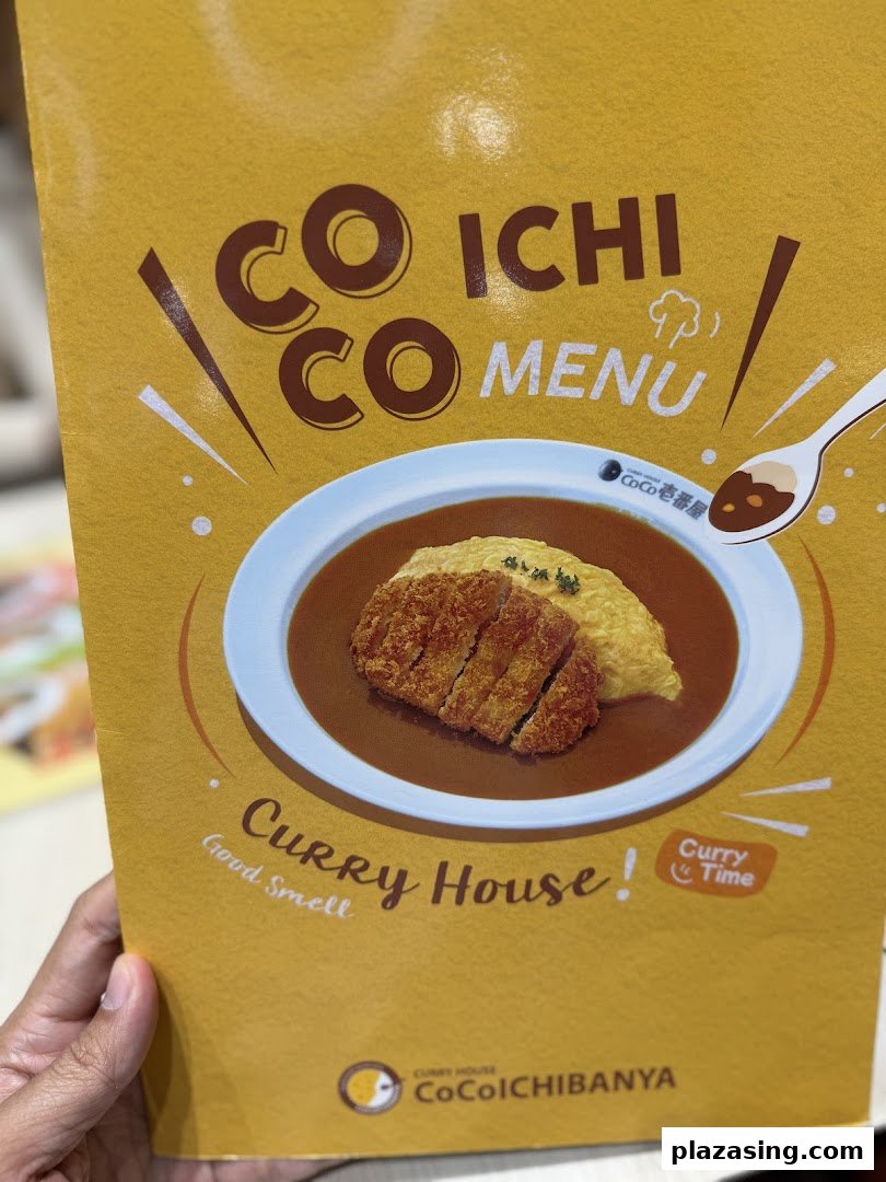 The vibrant yellow cover of a CoCo ICHIBANYA menu featuring a delicious katsu curry dish.