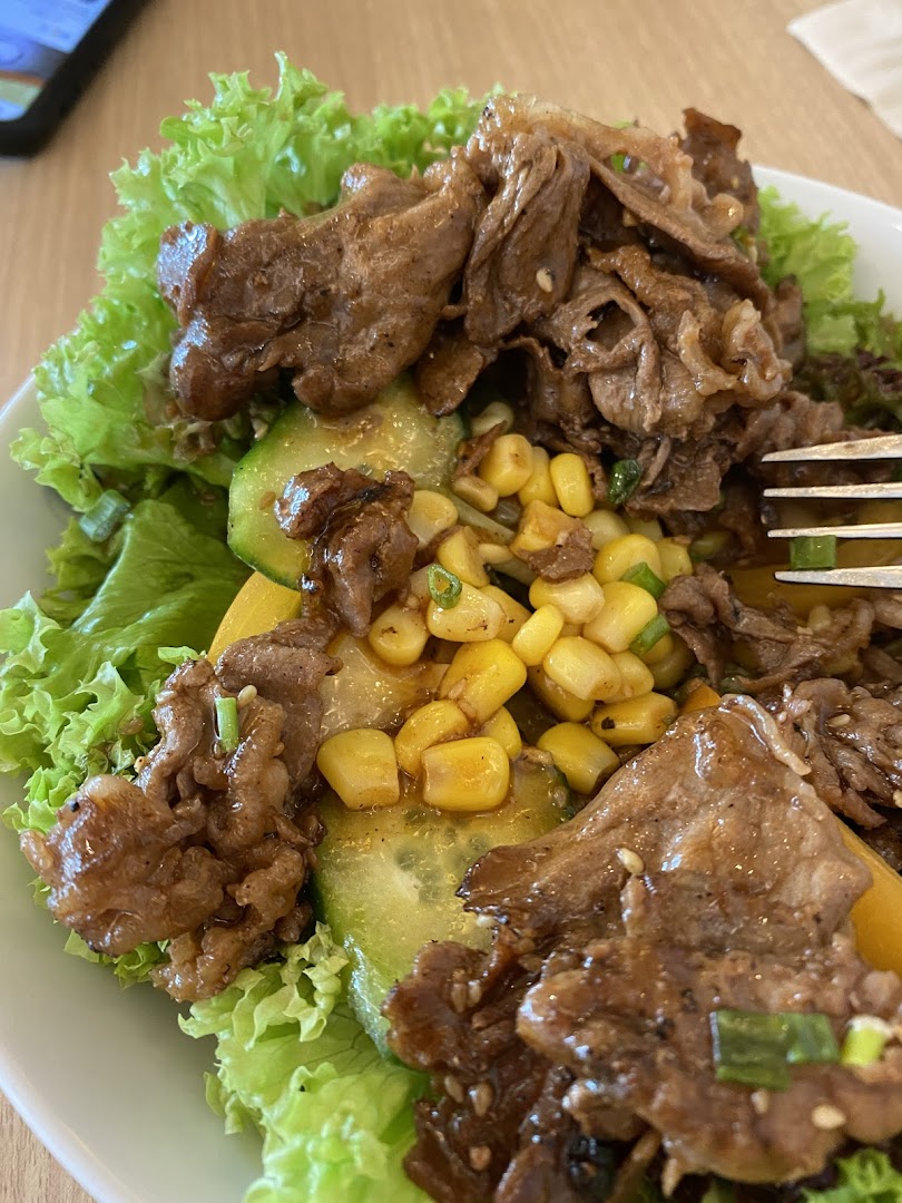 A close-up of a delicious beef and vegetable bowl with lettuce, corn, and cucumber.
