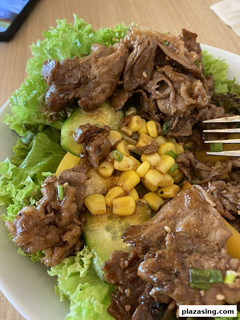 A close-up of a delicious beef and vegetable bowl with lettuce, corn, and cucumber.