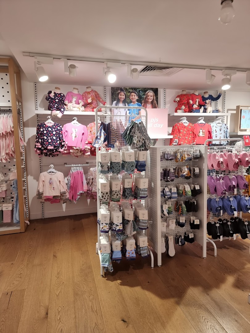 Interior view of Cotton On Kids, showcasing colorful children's clothing, pajamas, socks, and footwear on display.