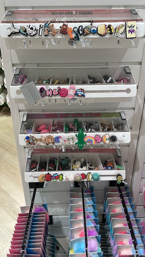 A display stand showcasing a wide variety of colorful Crocs Jibbitz charms for shoe customization.