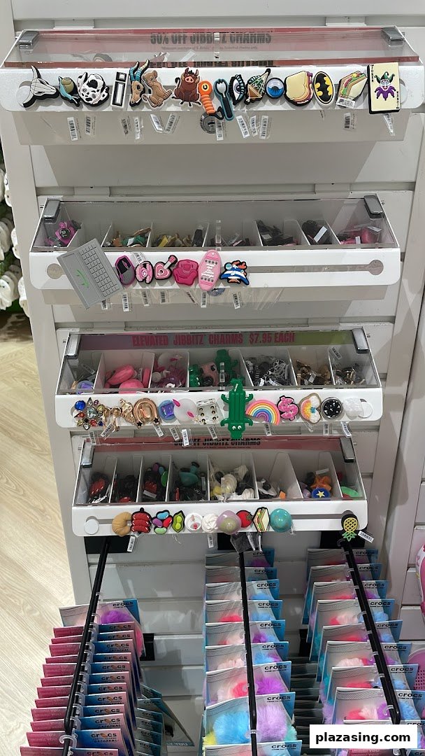 A display stand showcasing a wide variety of colorful Crocs Jibbitz charms for shoe customization.