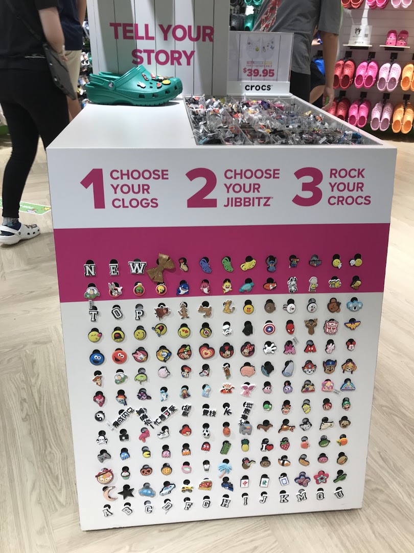 A Crocs in-store display showcasing Jibbitz charms for customizing clogs, inviting customers to personalize their footwear.