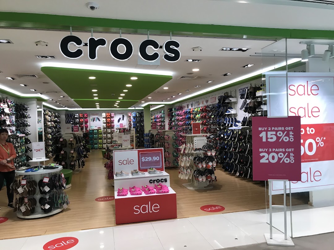 The Crocs store entrance features colorful displays of footwear and prominent sale signs.