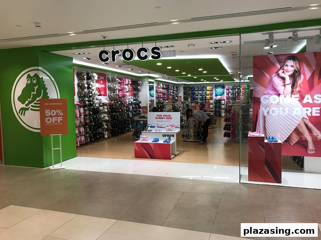 The vibrant Crocs store entrance features a large logo, colorful displays, and a 'Mid Season Sale' sign.