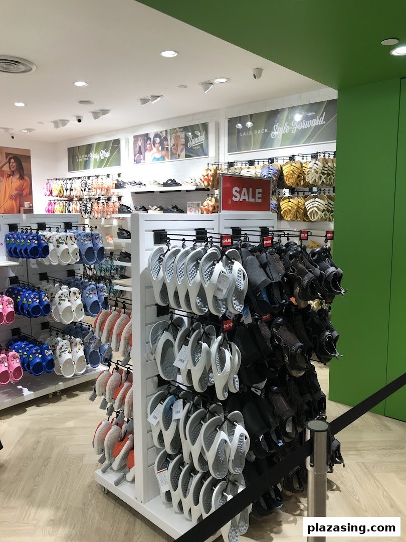 Interior view of a Crocs store showcasing a wide variety of colorful clogs, sandals, and flip-flops, including a sale section.