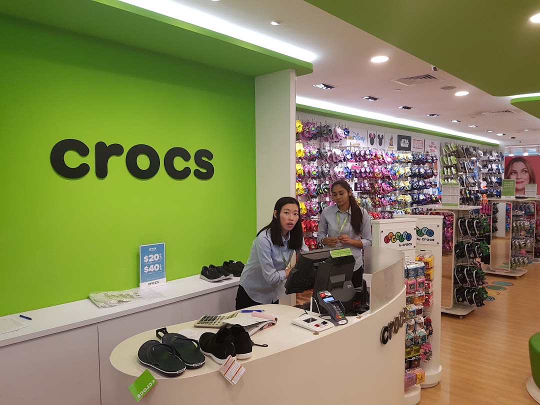 Interior view of a vibrant Crocs store with staff at the counter and colorful footwear displays.