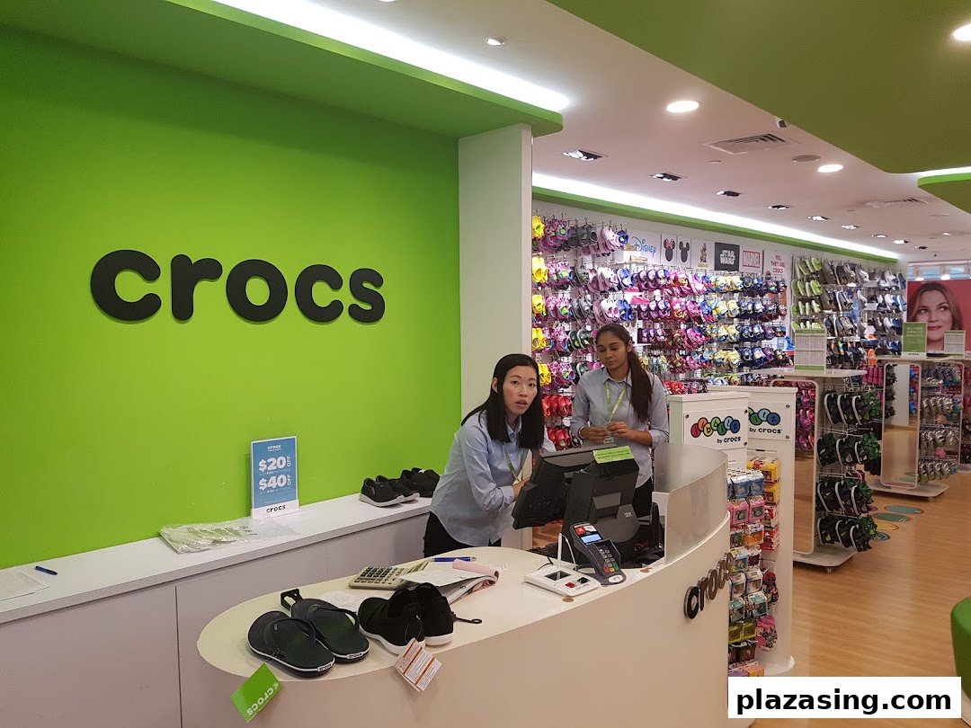 Interior view of a vibrant Crocs store with staff at the counter and colorful footwear displays.
