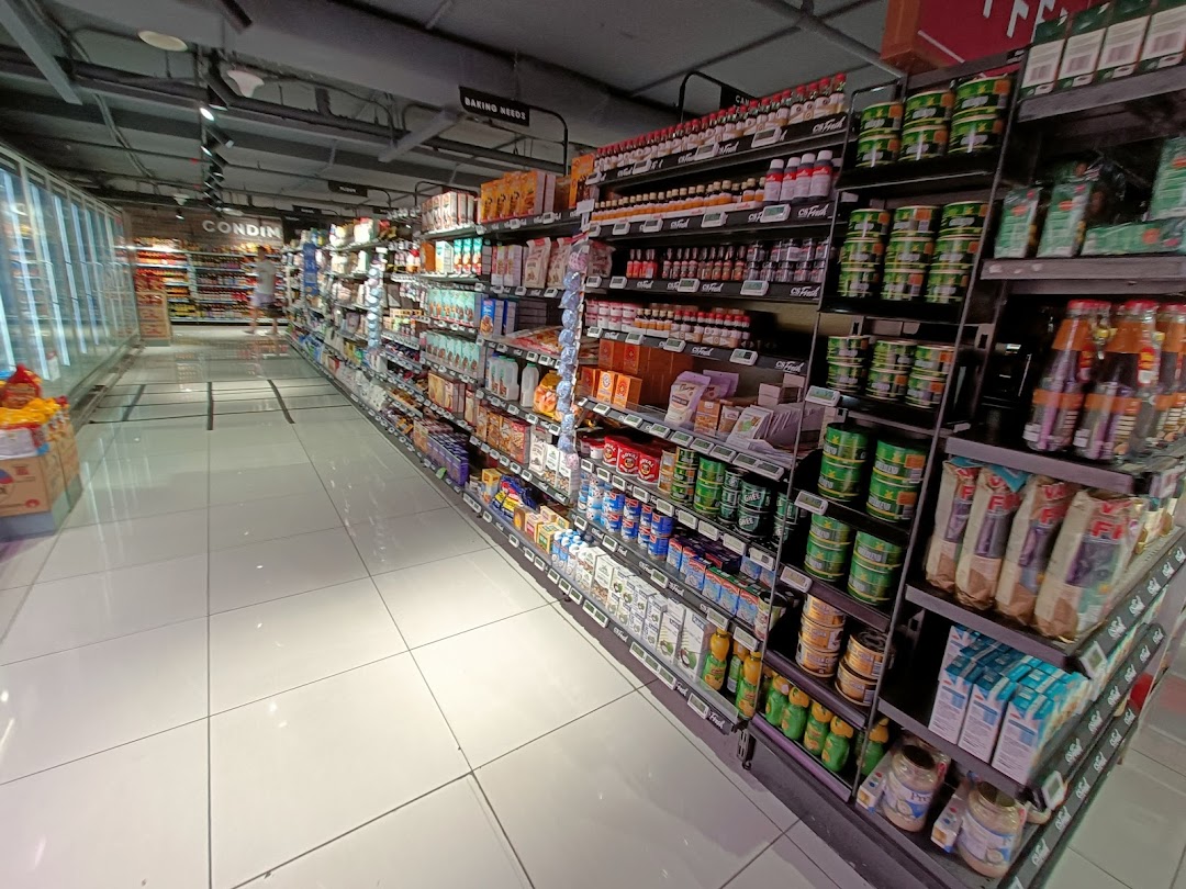 A brightly lit interior view of a CS Fresh supermarket aisle, showcasing a wide array of packaged goods and groceries.