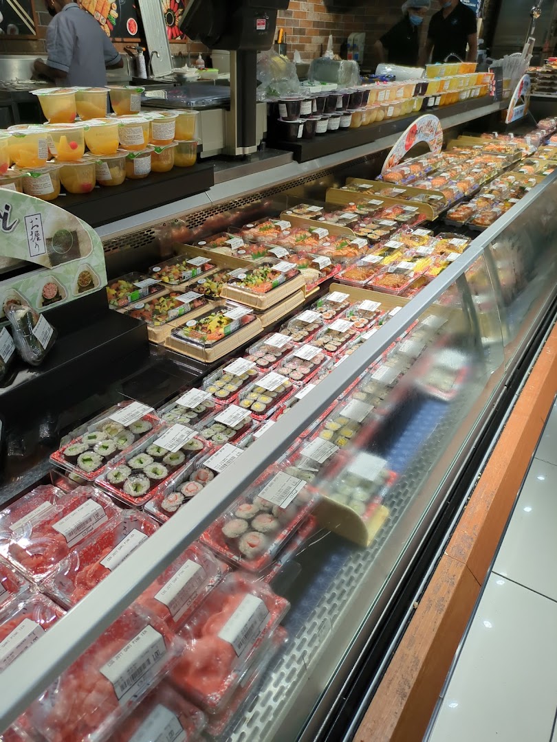 A refrigerated display case filled with various pre-packaged sushi, sashimi, and ready-to-eat meals.