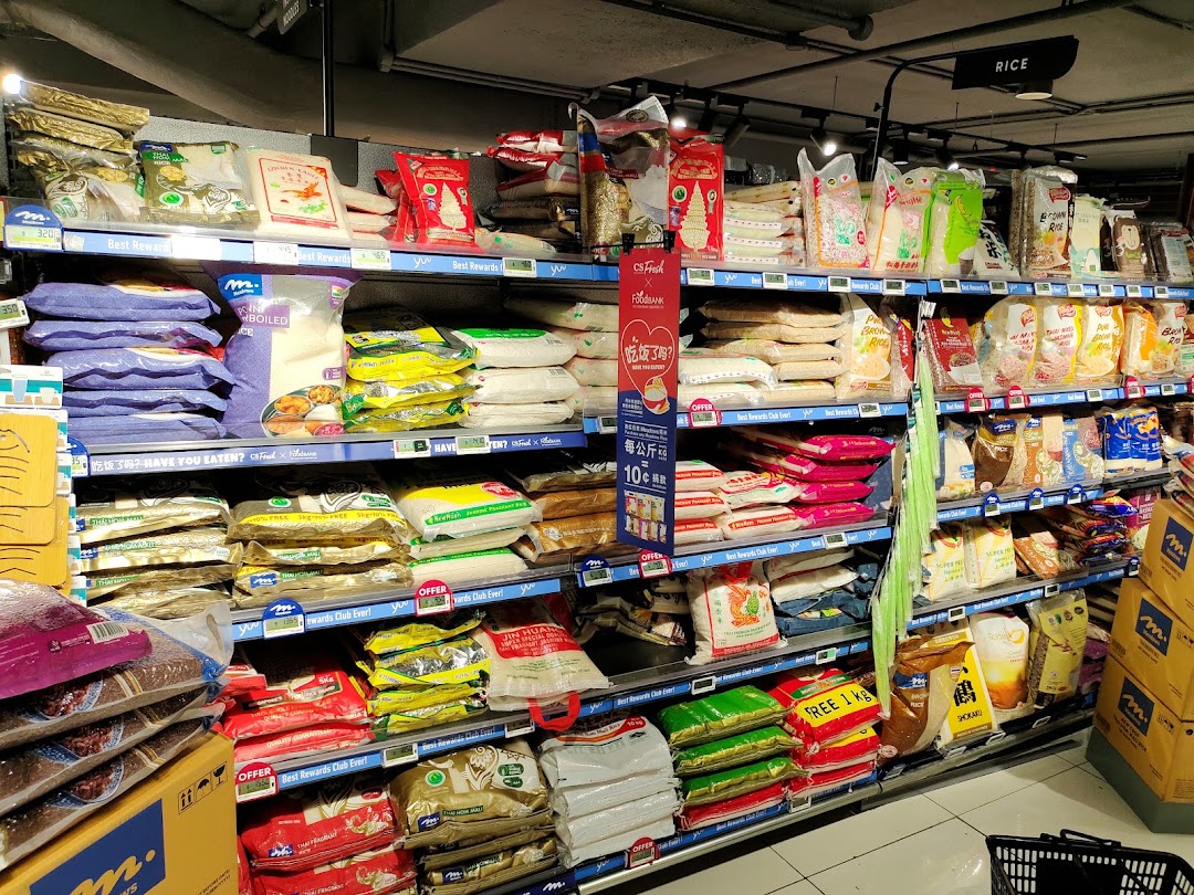 A well-stocked supermarket aisle displaying various types of rice and grains on multiple shelves.