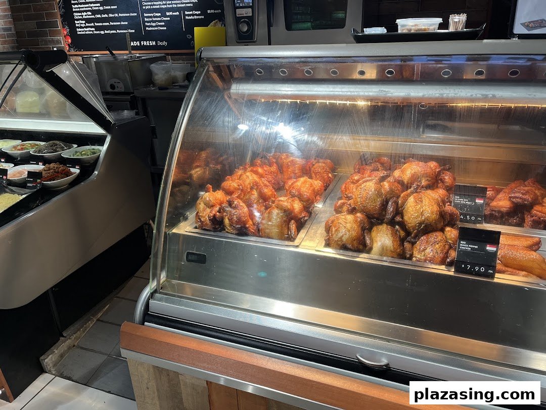 A deli counter at CS Fresh featuring roasted chickens, prepared salads, and a menu board.
