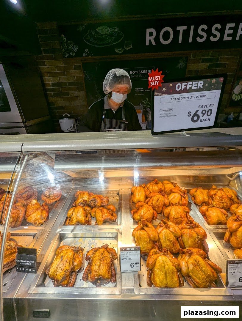 A staff member behind a display of freshly roasted rotisserie chickens and pork knuckles at CS Fresh.