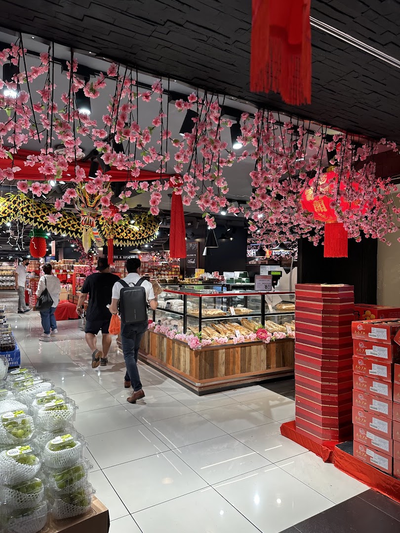 An interior view of CS Fresh, featuring a bakery display, shoppers, and festive cherry blossom decorations.