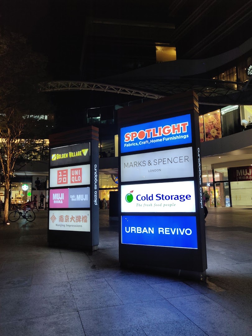 An illuminated directory sign at Plaza Singapura showcasing various retail and dining options at night.