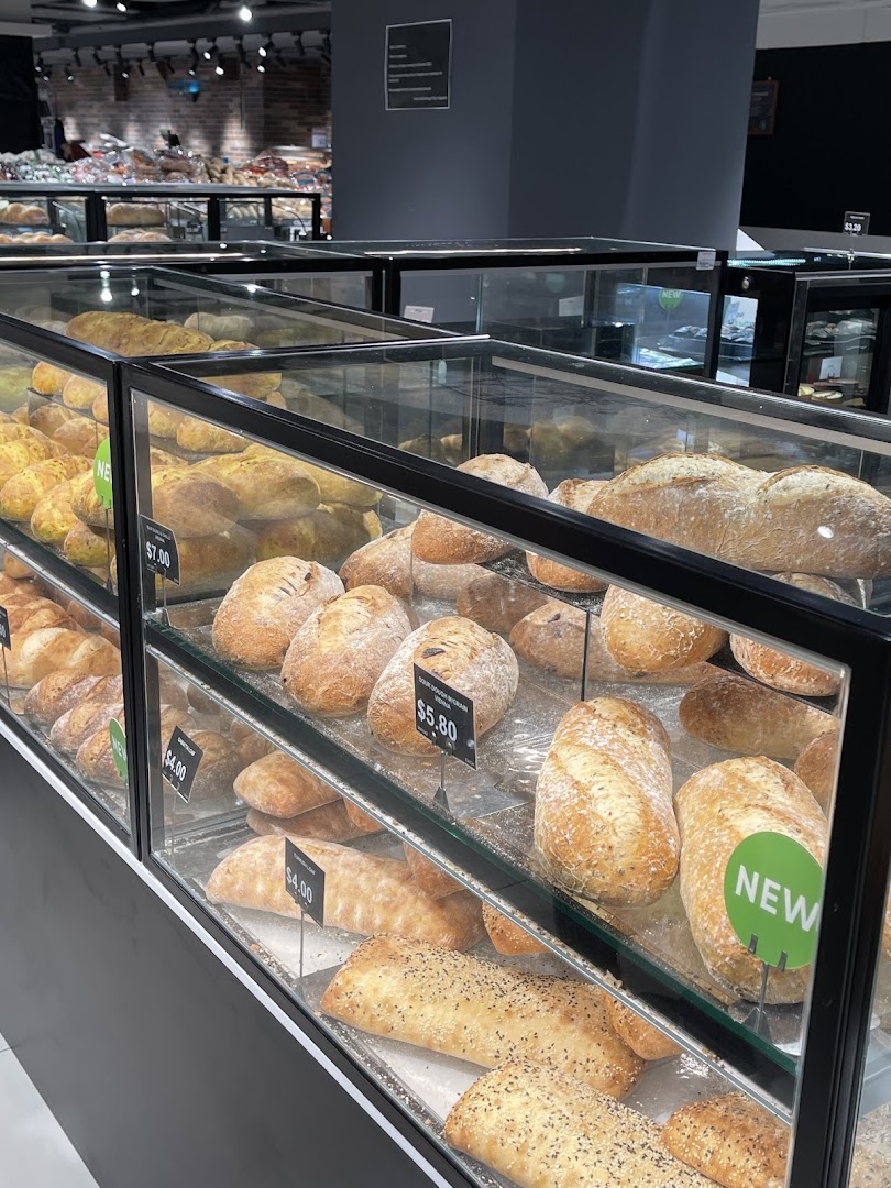 A vibrant display of freshly baked bread and pastries in a supermarket's bakery section.