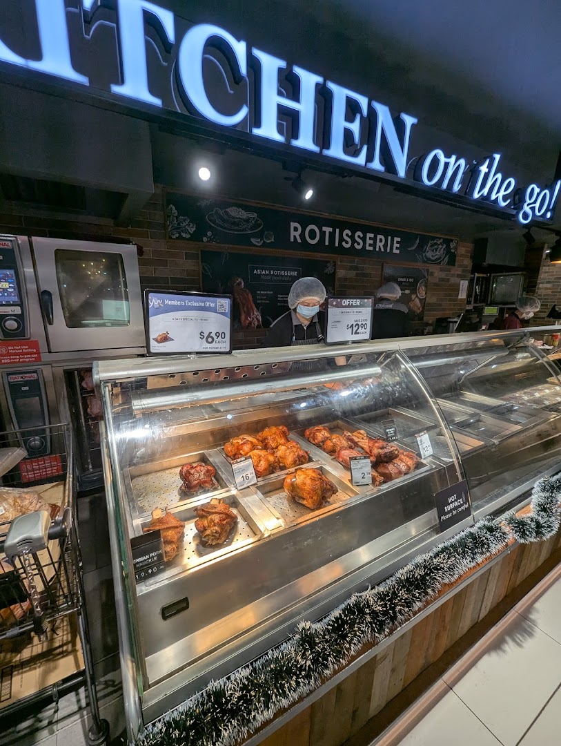 An interior shot of CS Fresh's 'Kitchen on the go!' rotisserie counter, featuring freshly cooked meats and staff.