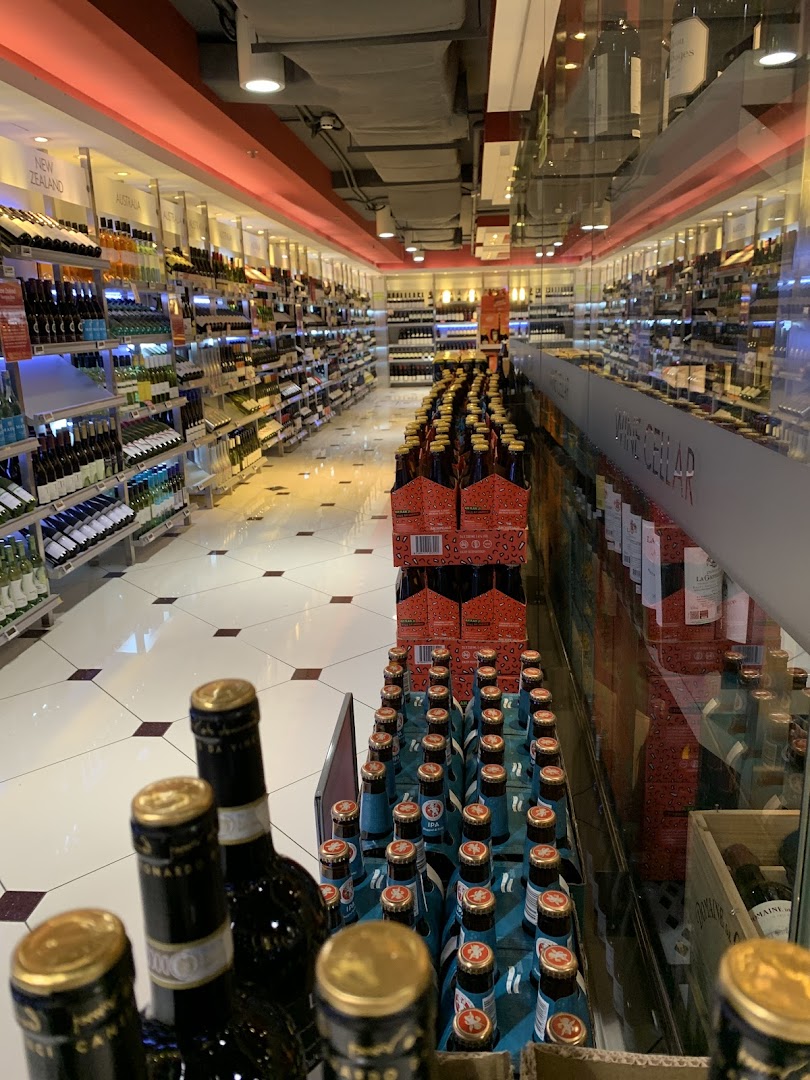An interior view of a well-stocked aisle in a supermarket, featuring a wide selection of wines and beers.