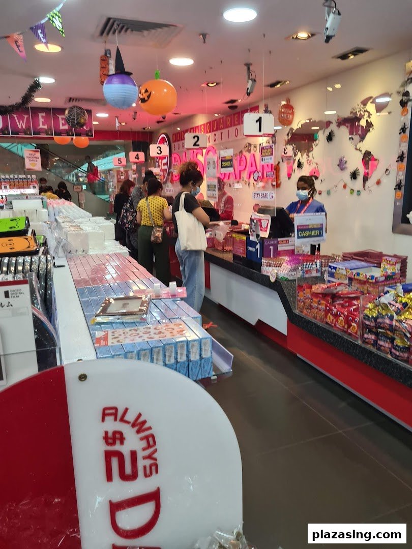 Customers queue at the checkout counter inside a Daiso store, featuring Halloween decorations and various products.