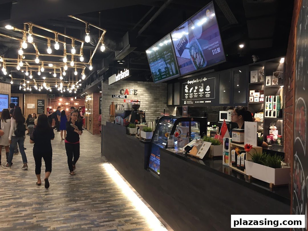 An interior view of a modern bank branch featuring a cafe counter, digital menus, and unique overhead lighting.
