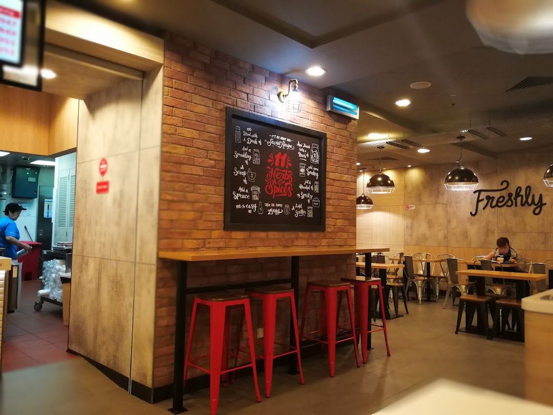 Interior view of a modern casual dining establishment with brick walls, red stools, and a kitchen area.