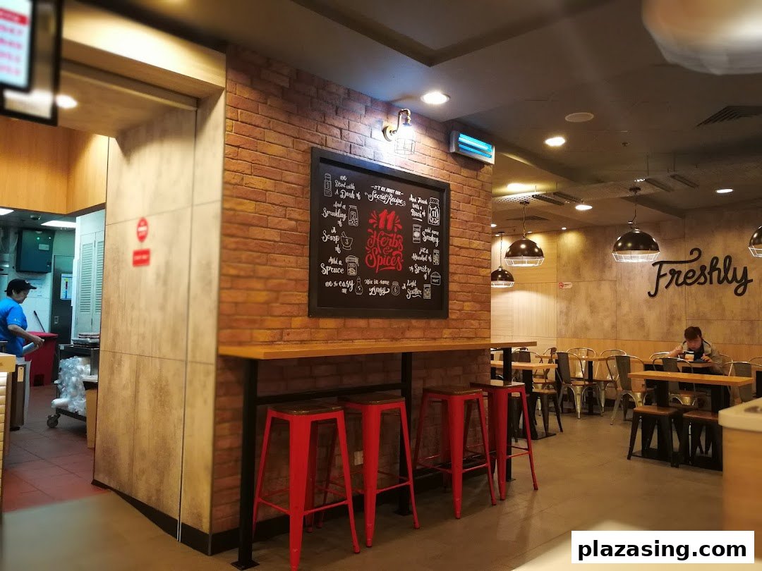 Interior view of a modern casual dining establishment with brick walls, red stools, and a kitchen area.