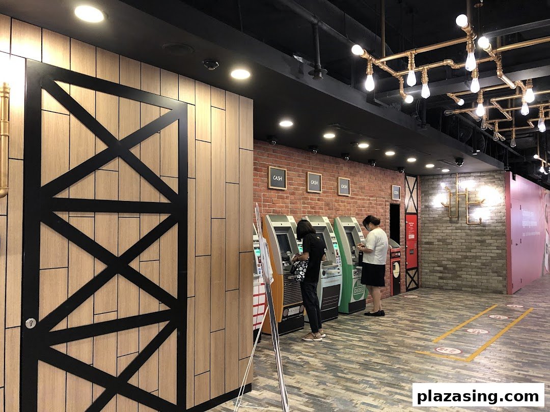 Customers utilize ATMs within the modern interior of a DBS bank branch at Plaza Singapura.