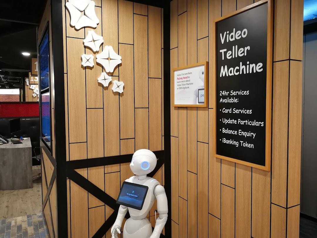 An interior view of DBS Plaza Singapura featuring a robot assistant and a sign for 24hr Video Teller Machine services.
