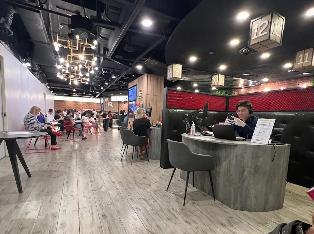 Interior view of a modern bank branch with customers seated in a waiting area and staff at service counters.