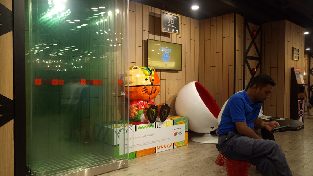 Interior view of DBS Plaza Singapura branch, featuring a colorful tiger statue, digital screens, and a customer.