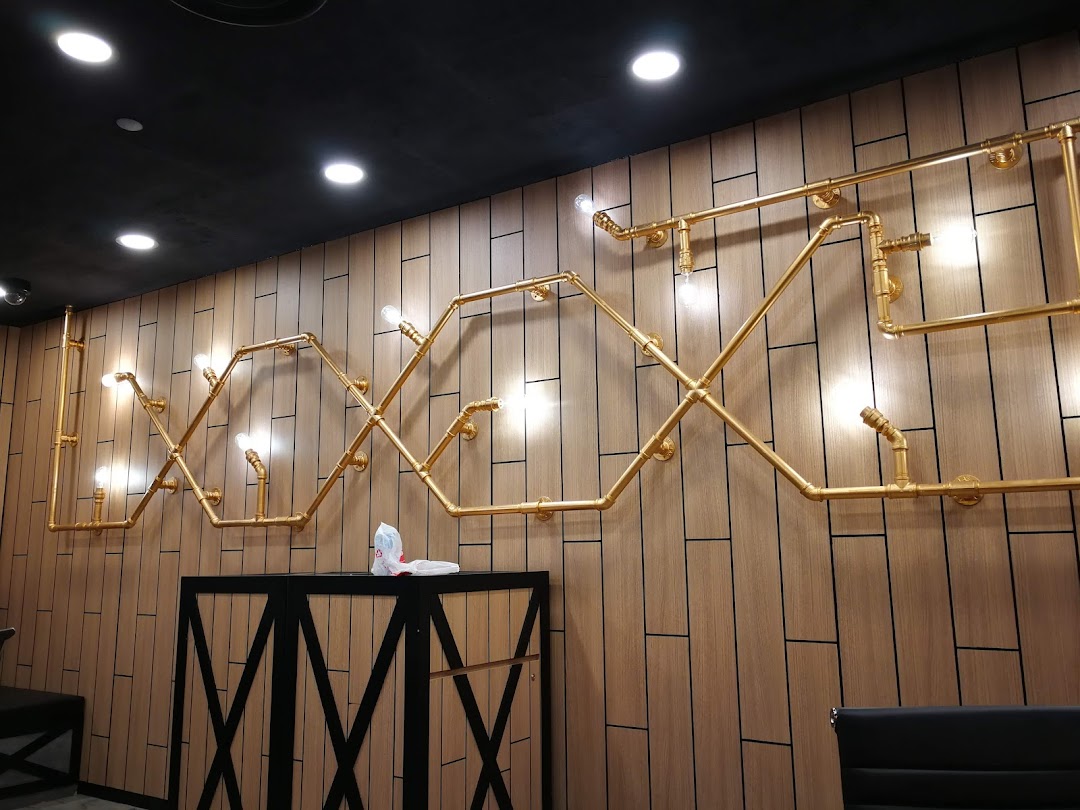 An interior shot showcasing a decorative wall with golden pipe-like light fixtures and a dark counter.