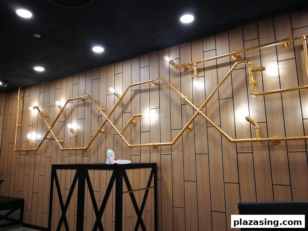 An interior shot showcasing a decorative wall with golden pipe-like light fixtures and a dark counter.