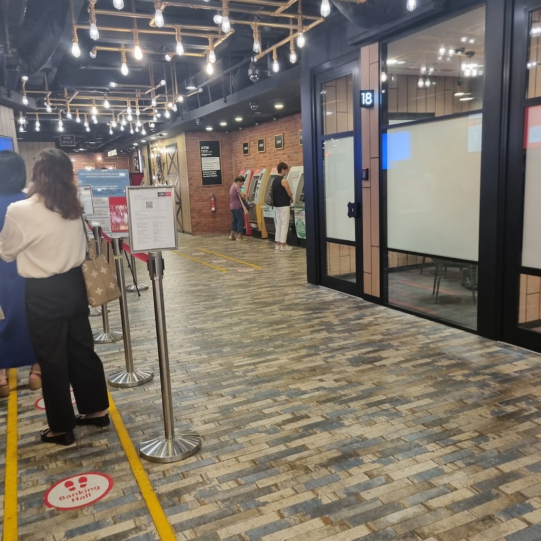 Customers queue and use ATMs inside the modern DBS Plaza Singapura bank branch.