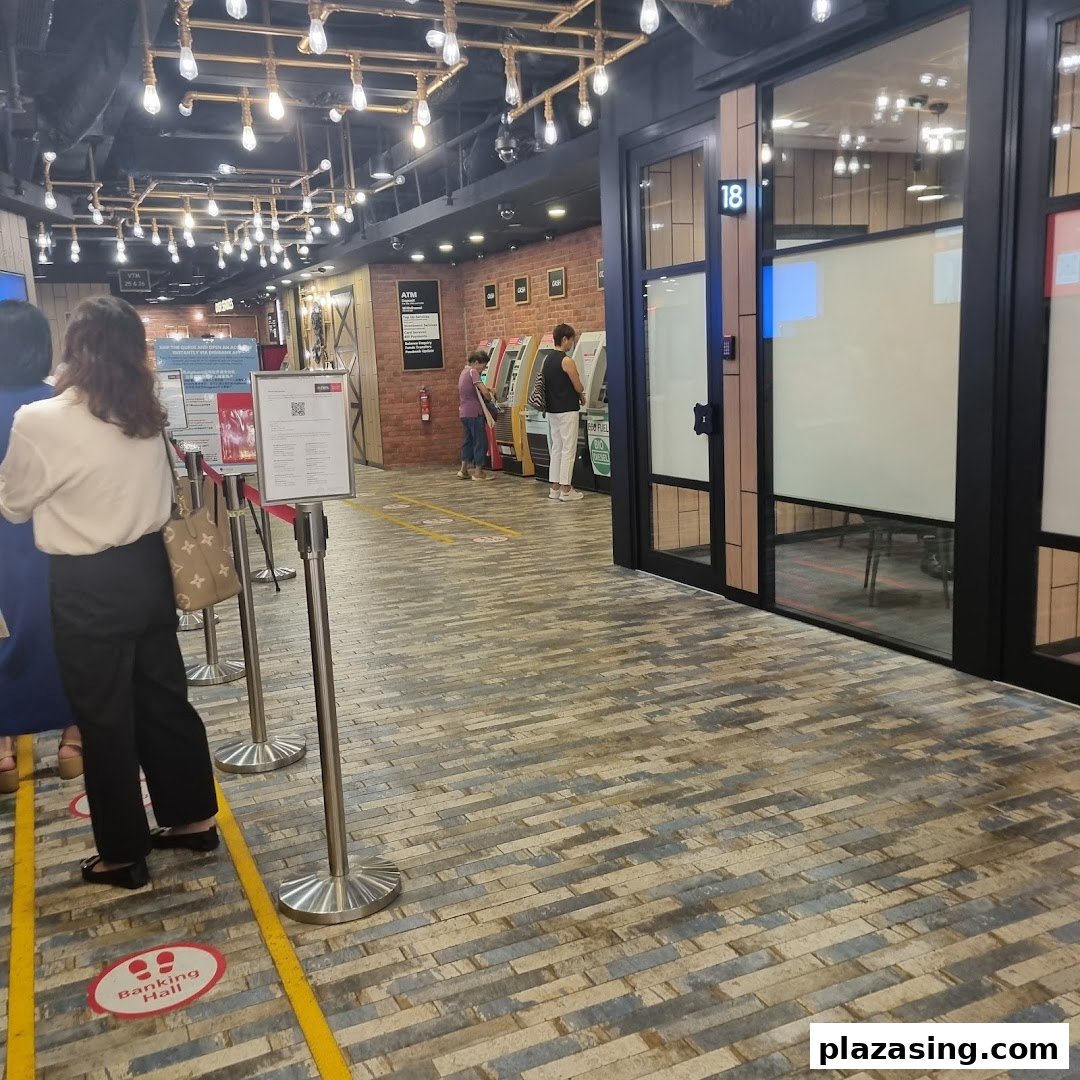 Customers queue and use ATMs inside the modern DBS Plaza Singapura bank branch.