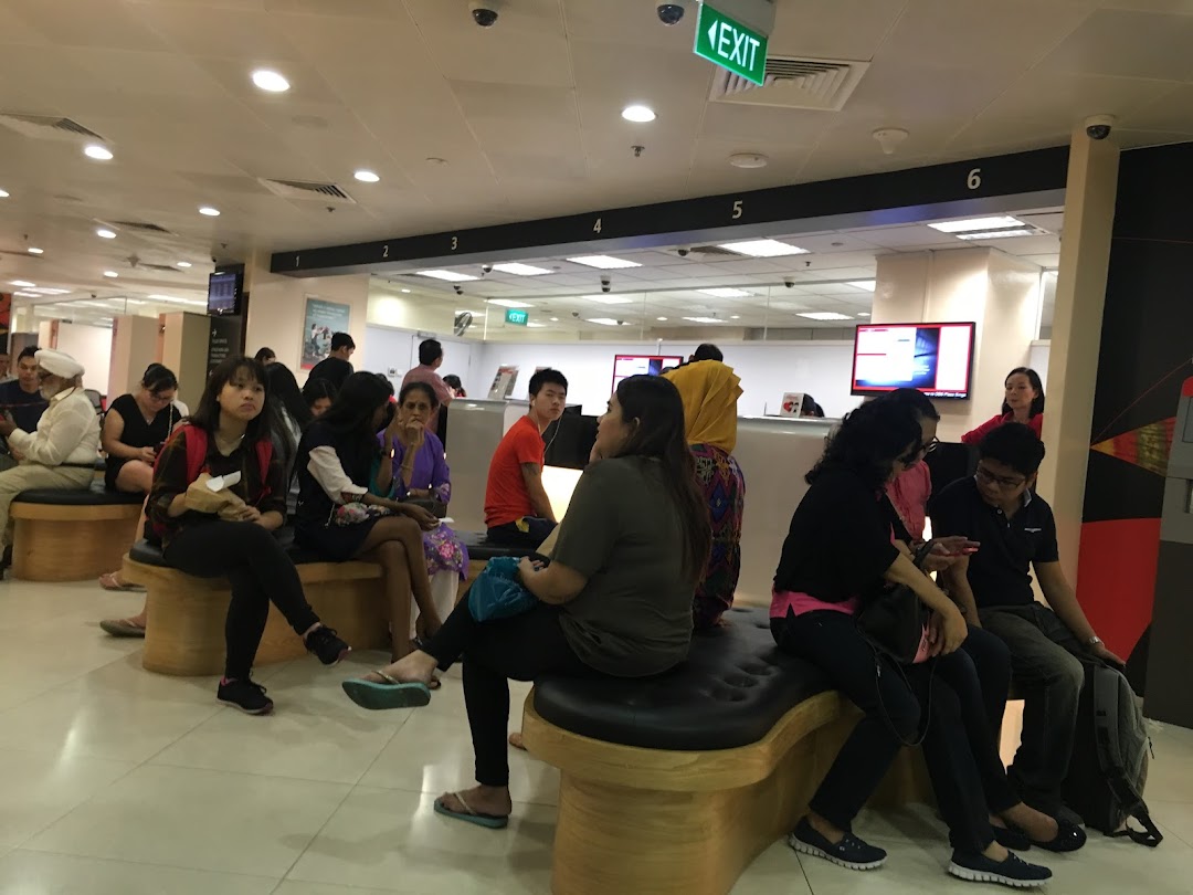 Customers wait in a spacious, well-lit service center with multiple counters and an exit sign visible.